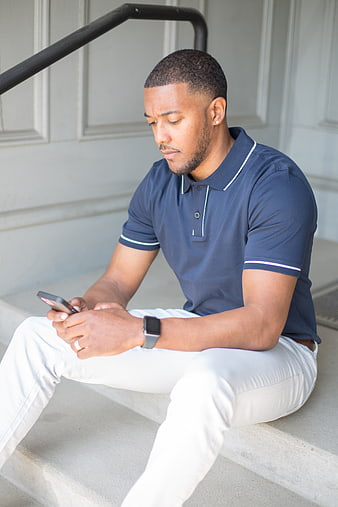 Young Black Man Sitting on Steps Using Smartphone