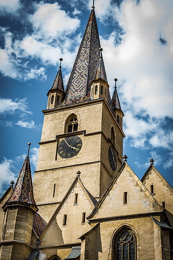 Low angle view of historic church tower with colorful tiled spire