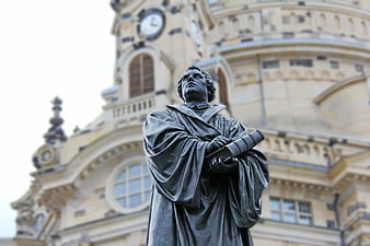 Bronze Statue of Man with Book in Front of Historic Building