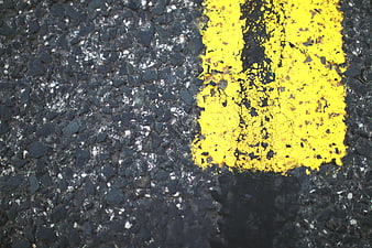Close-up of worn yellow road marking on asphalt