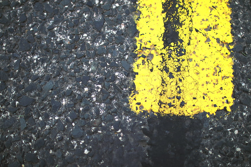 Close-up of worn yellow road marking on asphalt
