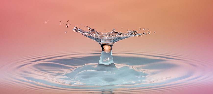 Macro water droplet splash with ripples on pastel gradient background