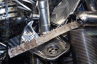Close-up of stacked stainless steel kitchenware and saw blade