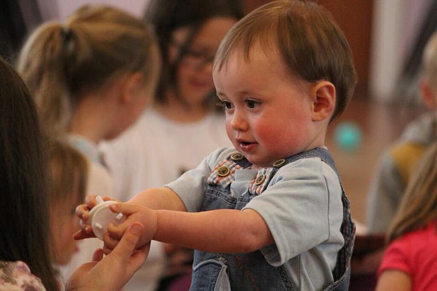 Toddler boy in denim overalls playing with toy