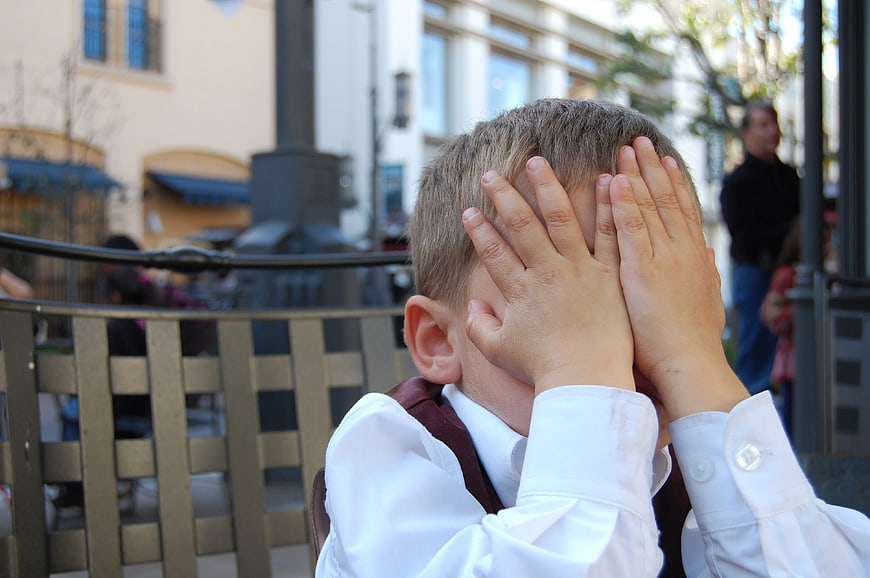 Young boy covering face with hands in frustration