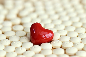 Red Heart Shaped Pill Among White Tablets