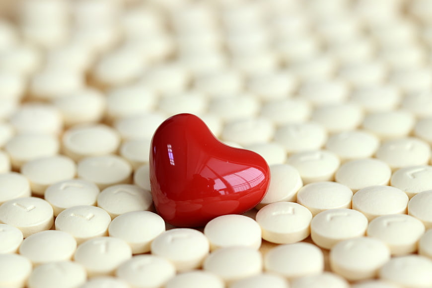 Red Heart Shaped Pill Among White Tablets