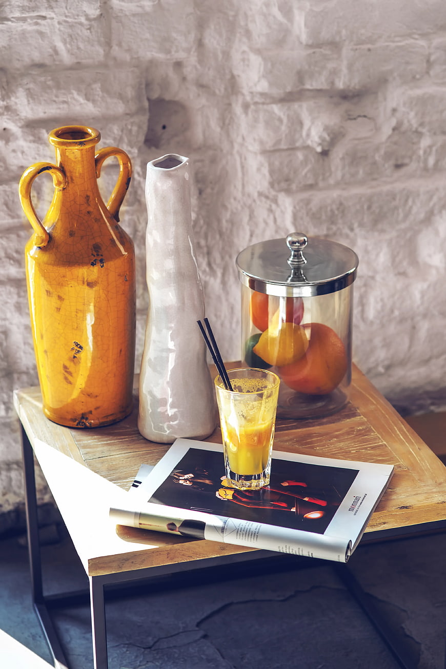 Fresh orange juice on wooden table with magazines and vases