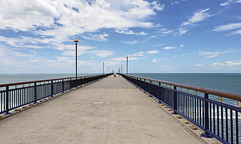 Long Pier Extending into Ocean Under Blue Sky