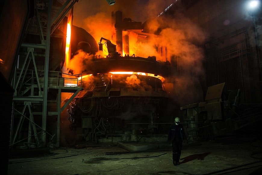 Industrial Worker Walking Near Glowing Molten Steel Blast Furnace