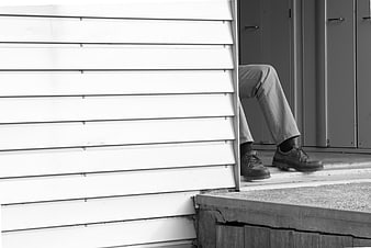 Man's legs and shoes sitting on a porch step