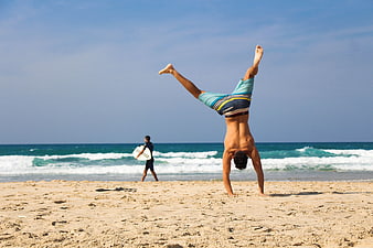 Athletic Man Doing Handstand on Sandy Beach