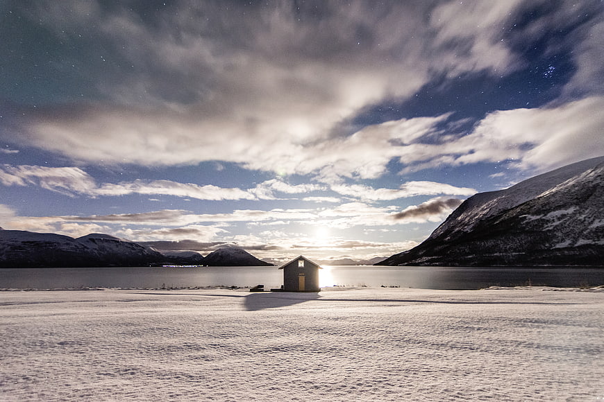 Lone Cabin in Snowy Winter Landscape Under Starry Sky