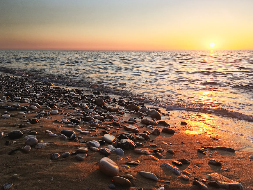 Sunset on Rocky Pebble Beach with Golden Ocean Waves