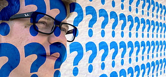 Man with glasses and blue question marks conceptual portrait