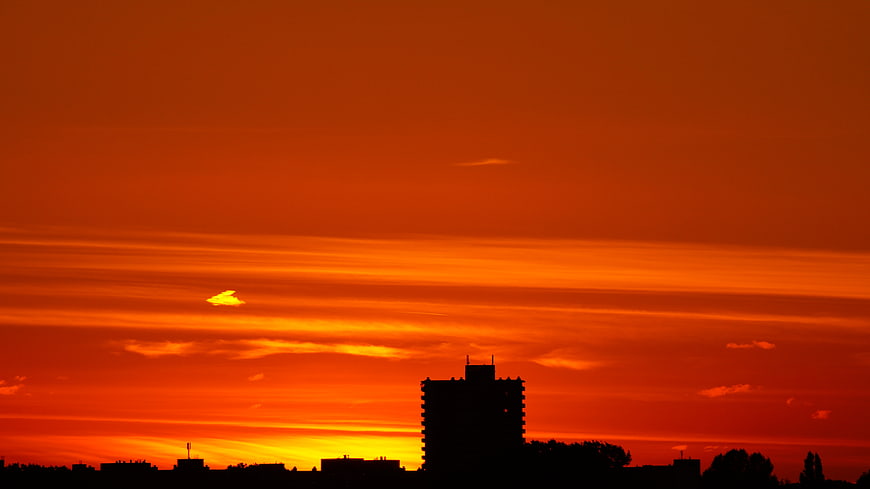 Silhouette of City Skyline Against Vibrant Orange Sunset Sky