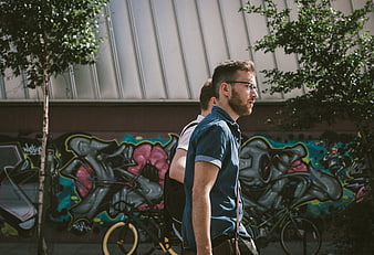 Two Men Walking Past Colorful Graffiti Wall in Urban Street