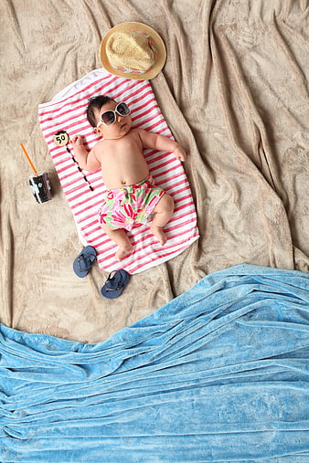 Cute baby wearing sunglasses lying on striped beach towel