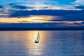 Lone Sailboat on Lake at Sunset with Golden Reflections