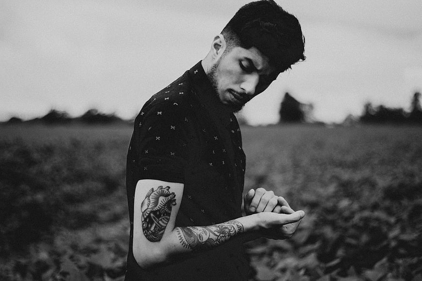 Black and white portrait of tattooed man looking down
