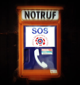 Illuminated Orange Emergency SOS Telephone Box at Night