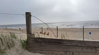 Overcast Beach Scene with Wooden Fence and Sand Dunes