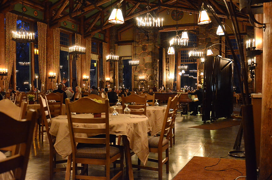 Luxurious rustic lodge restaurant interior with candlelit tables and stone fireplace
