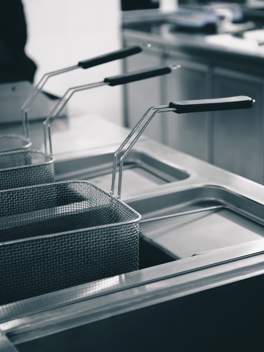 Stainless steel deep fryer baskets in commercial kitchen