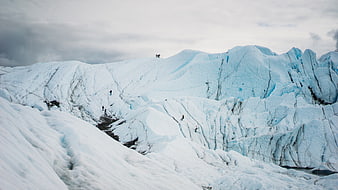 Hikers climbing a massive blue glacier landscape