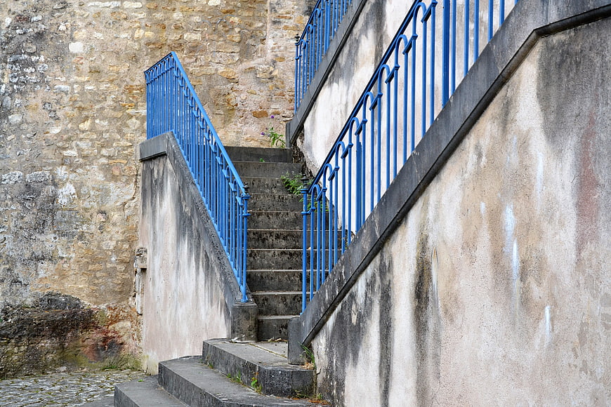 Blue metal railing on old stone staircase in historic alley