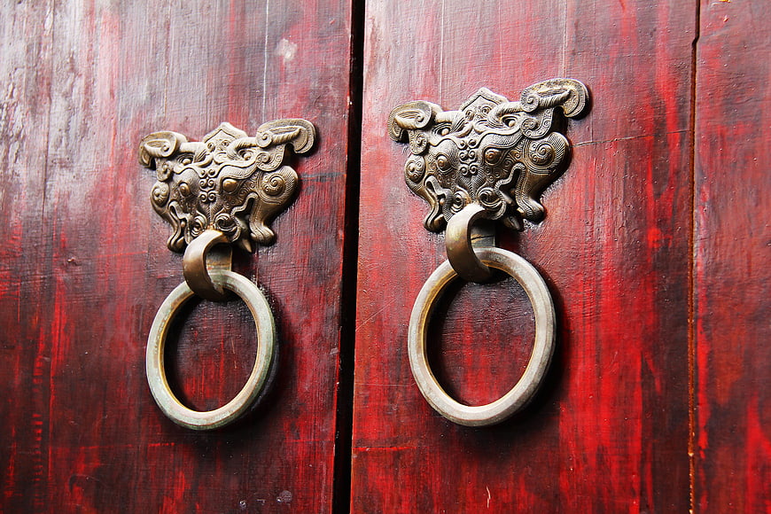Traditional Chinese Bronze Door Knocker on Red Wooden Door