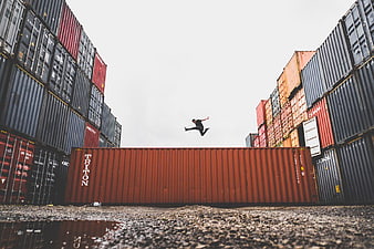 Man Jumping Between Shipping Containers at Industrial Port