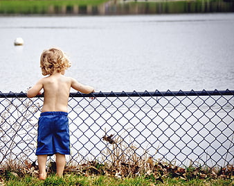 Toddler Boy Looking at Lake Through Fence