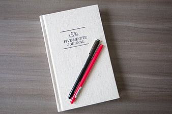 The Five-Minute Journal with Pens on Wooden Desk