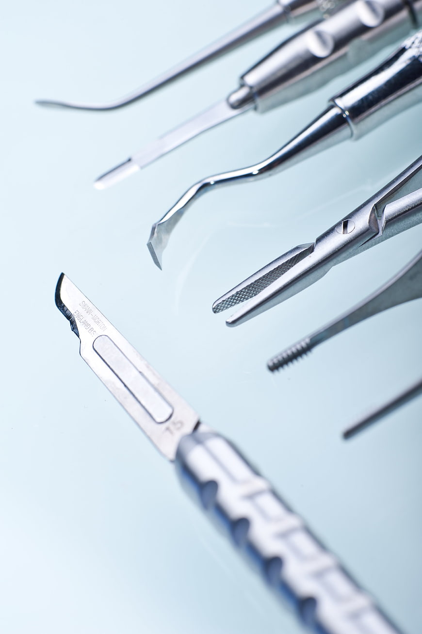 Close-up of stainless steel dental instruments on a light blue background
