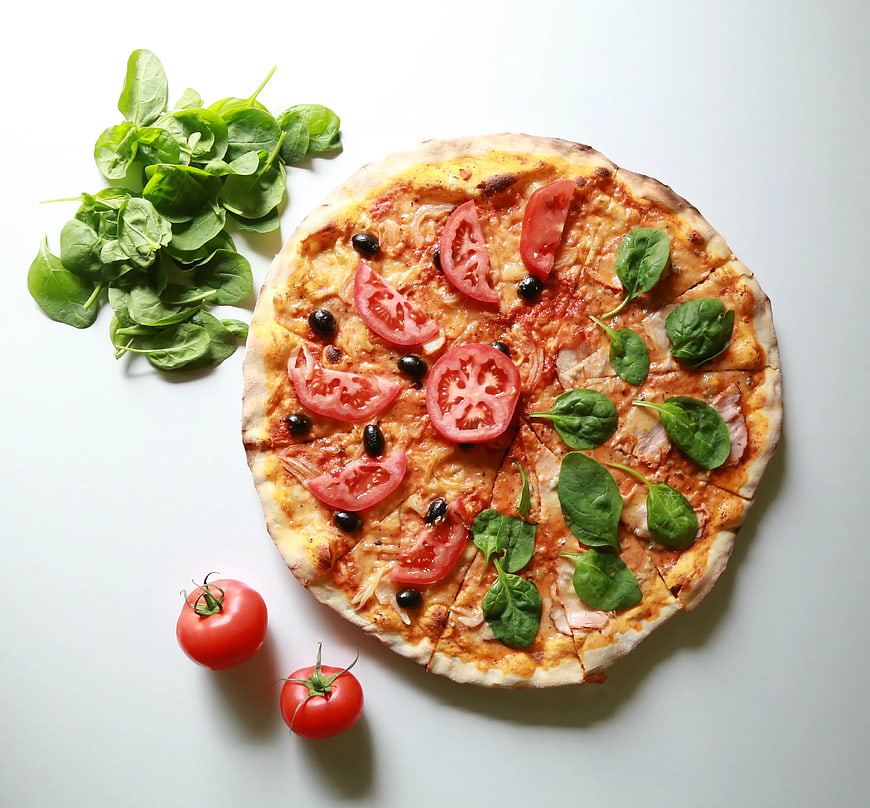 Top view of homemade pizza with tomatoes and spinach