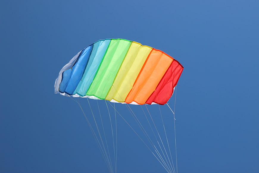 Colorful Rainbow Kite Flying Against Clear Blue Sky