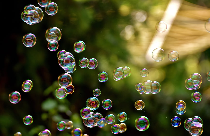 Iridescent soap bubbles floating against a blurred green background