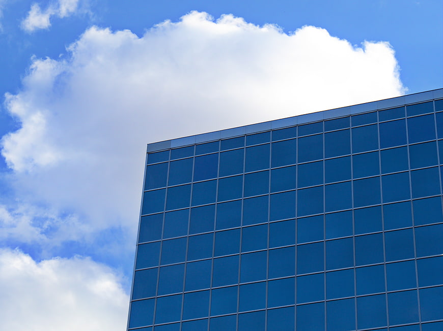 Modern Glass Office Building Facade Against Blue Sky