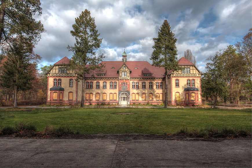 Abandoned Historic Sanatorium Building With Red Roof And Autumn Trees