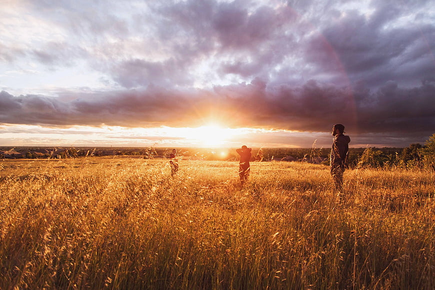 Silhouetted People in Golden Wheat Field at Sunset