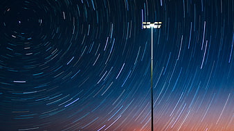 Star trails circling a stadium light pole at night