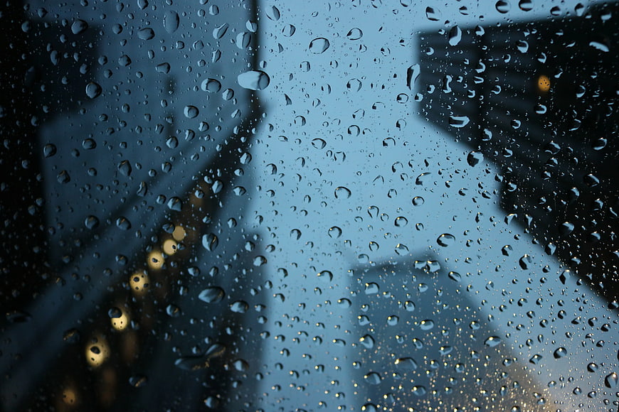 Raindrops on window glass with blurred city lights background
