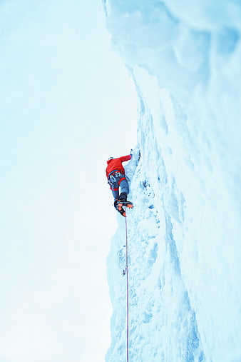 Ice Climber Scaling Vertical Frozen Waterfall in Red Jacket
