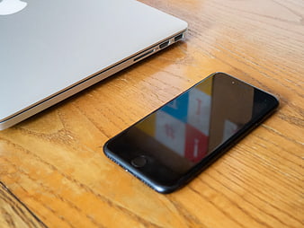 Black Smartphone and Silver Laptop on Wooden Desk