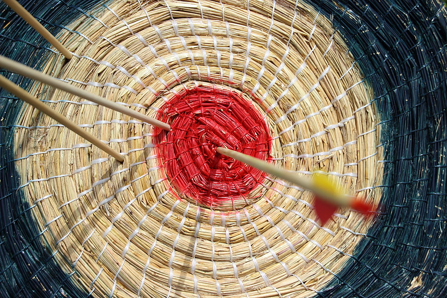 Close-up of arrows hitting the bullseye of a straw archery target