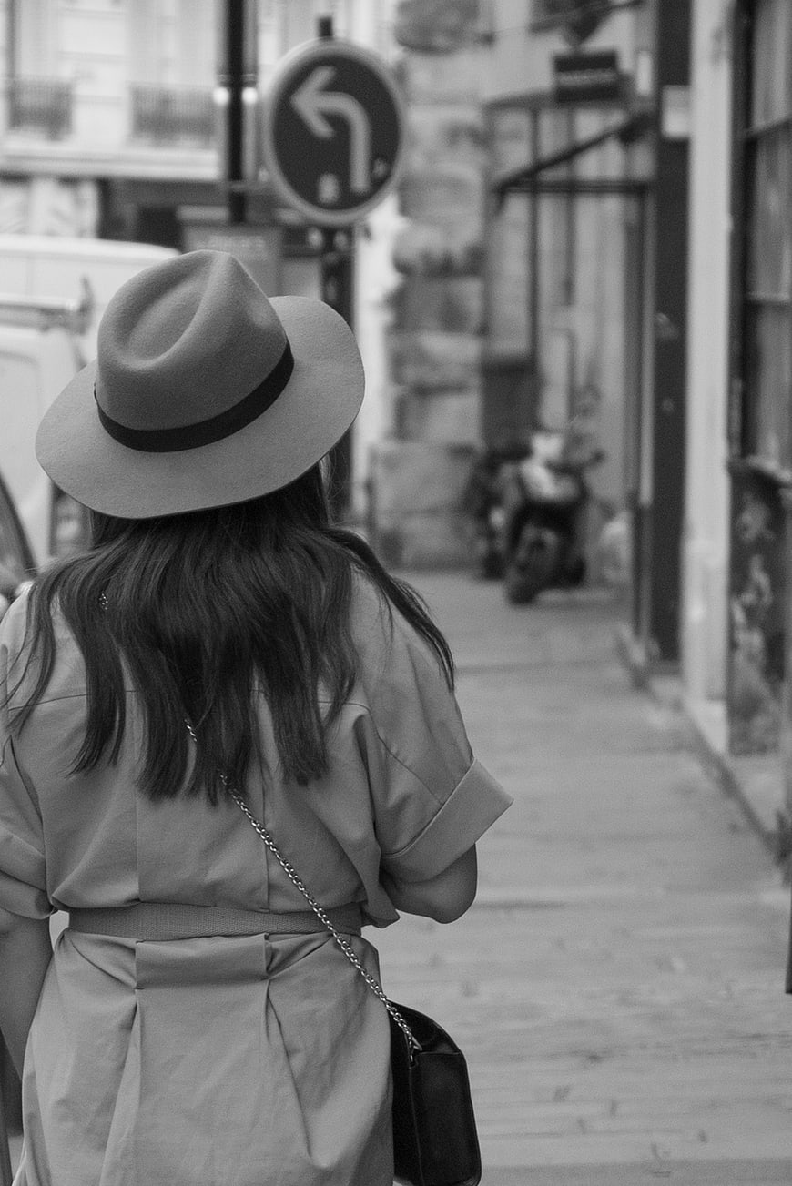 Woman in Fedora Hat Walking Down City Street