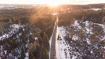 Aerial View of Snowy Forest Road at Sunset