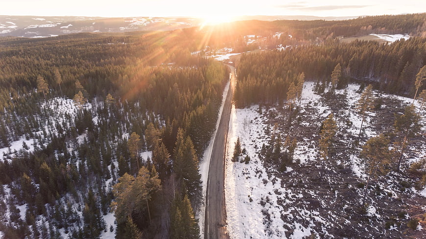 Aerial View of Snowy Forest Road at Sunset
