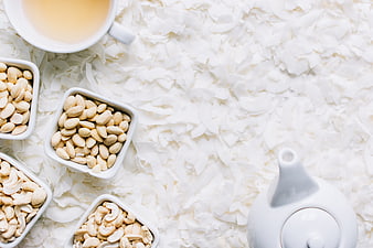 Flat lay of nuts, tea, and coconut flakes on white background